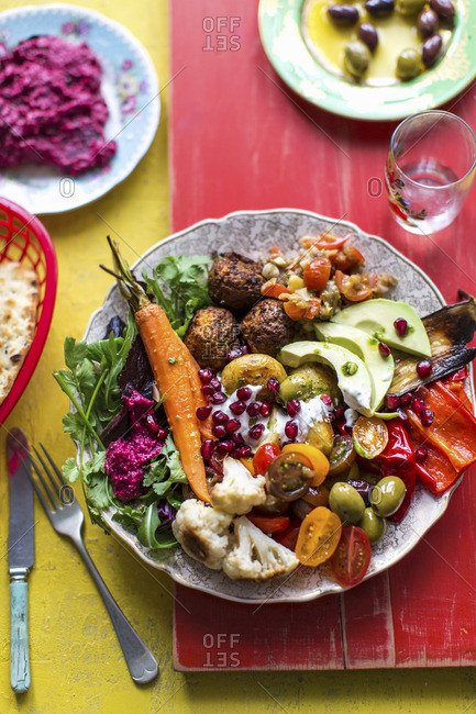 Beetroot hummus, falafel, flat bread, mezze, mutabal, olives, peppers, pommigranet, roast carrots, roast cauliflower, roast potates, salad