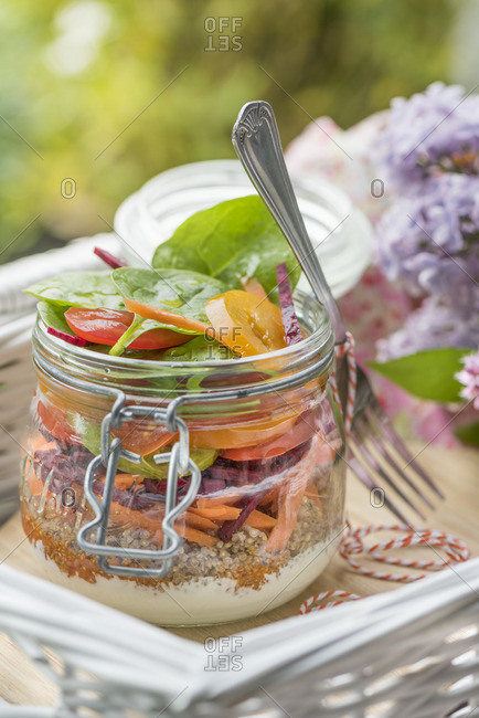 Layered salad with qunioa and vegetables in a jar for a summer picnic