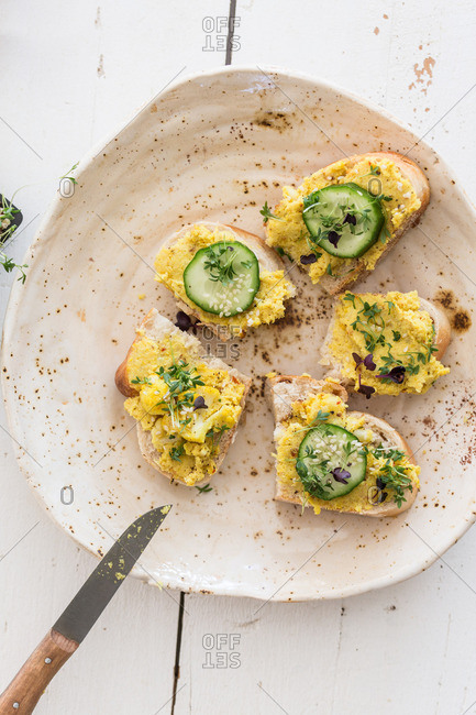 Open sandwiches topped with a turmeric spread, cucumber slices and cress