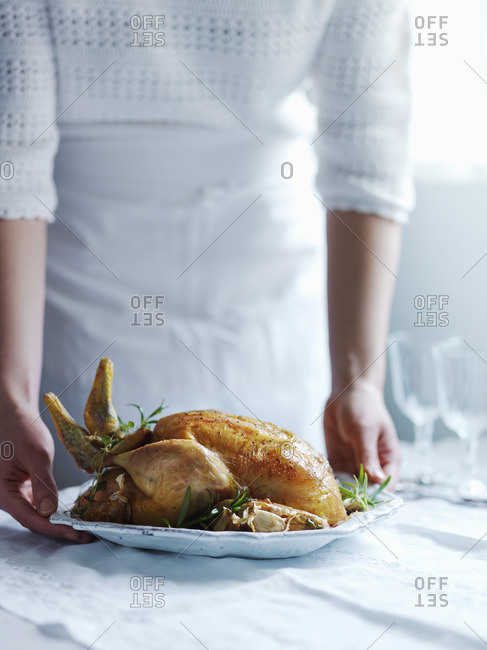 A woman serving roast chicken with thyme