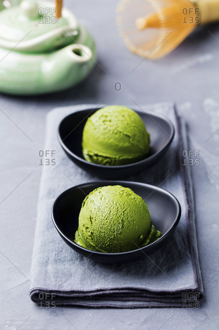 Matcha ice cream scoop in bowl on a grey stone background