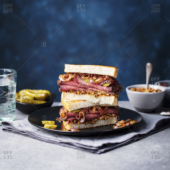 Roast beef sandwich on a plate with pickles