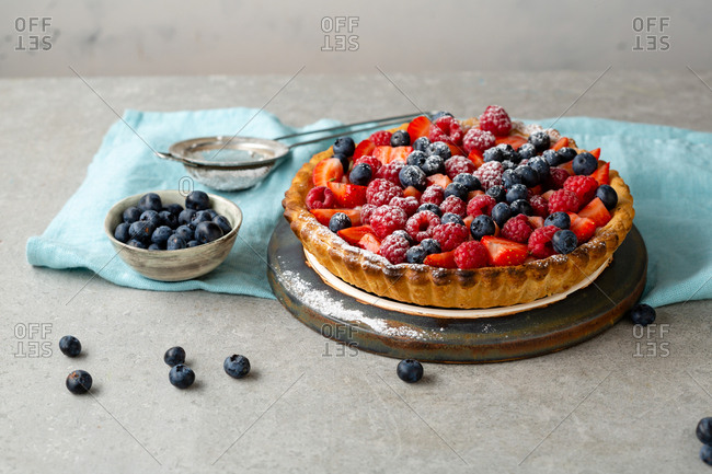Summer berry tart sprinkled with powdered sugar