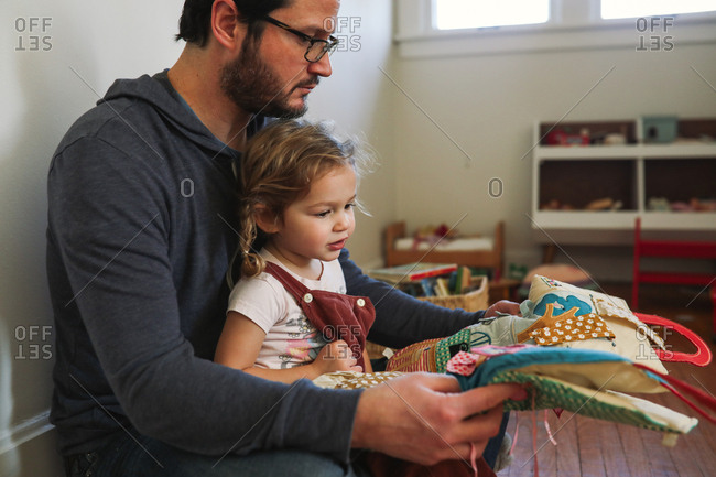 Father reading fabric book to toddler daughter