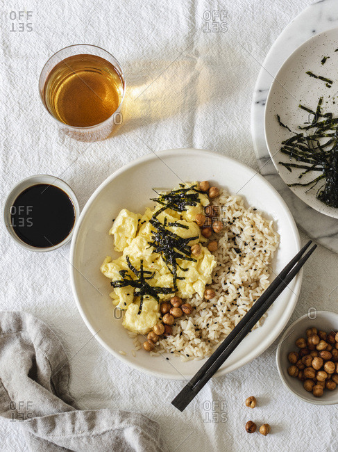 Japanese style scrambled eggs with rice chickpeas and nori served in white bowl with chopsticks