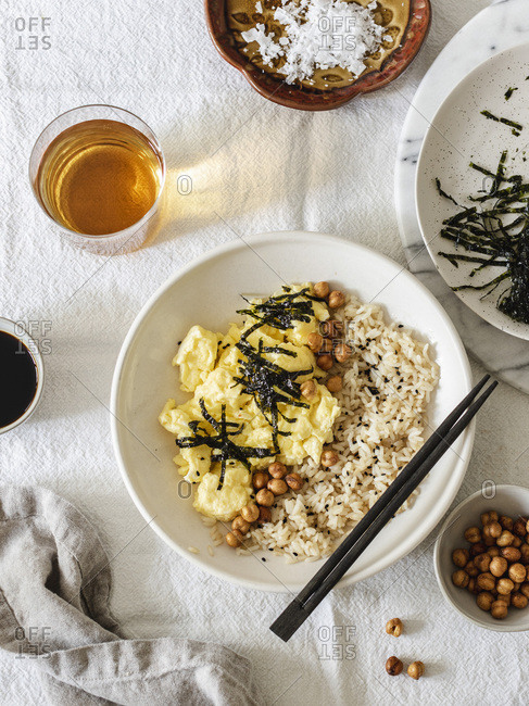 Japanese style scrambled eggs with rice chickpeas and nori served in white bowl with chopsticks