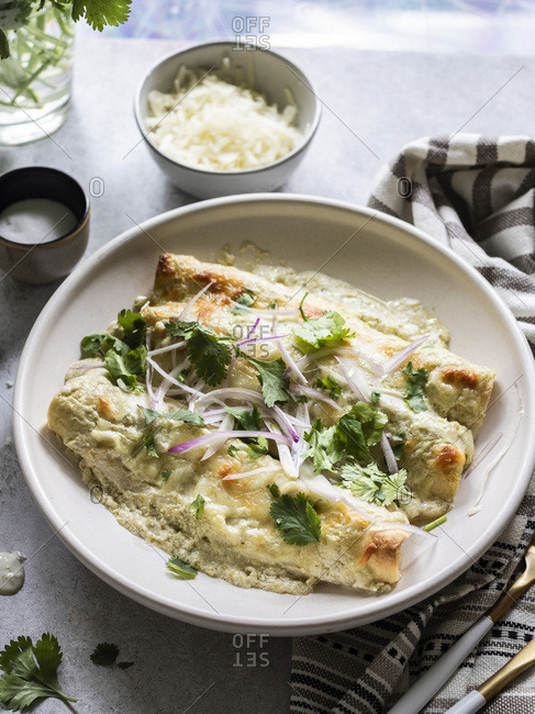 Cheesy enchiladas filled with chredded chicken and black beans, served with  creamy sauce