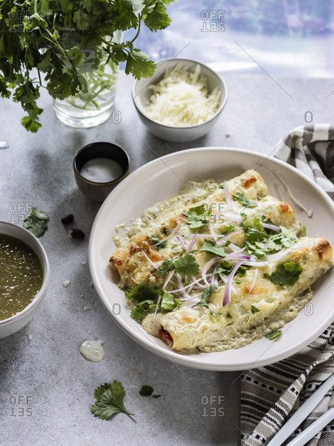 Cheesy enchiladas filled with chredded chicken and black beans, served with  creamy sauce