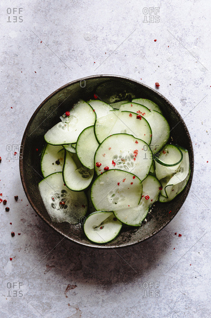 sliced cucumber and pink peppercorn into a black bowl