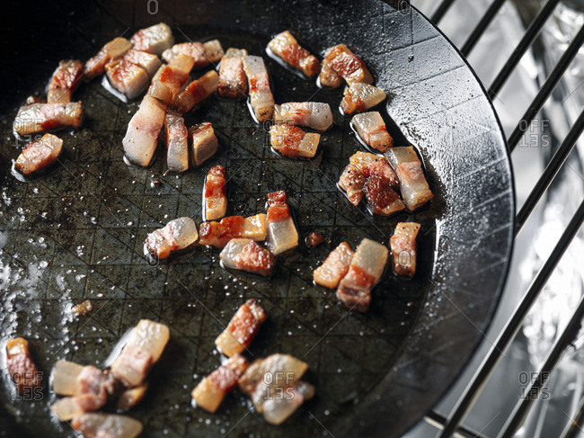 Bacon frying in stove top pan. Sizzling bacon strips in silver skillet.  Stock Photo