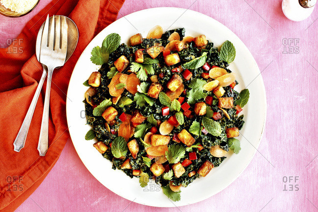 Roasted Potato Kale Salad with Cilantro Mint Vinaigrette photographed on a pink background