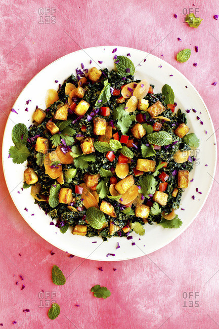 Roasted Potato Kale Salad with Cilantro Mint Vinaigrette photographed on a pink background