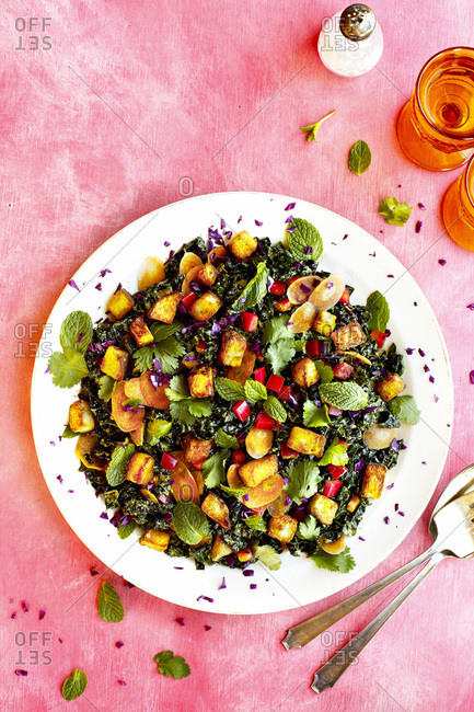 Roasted Potato Kale Salad with Cilantro Mint Vinaigrette photographed on a pink background