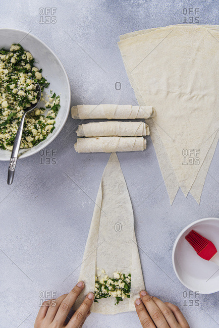 Woman making Turkish borek with phyllo sheets and cheese filling