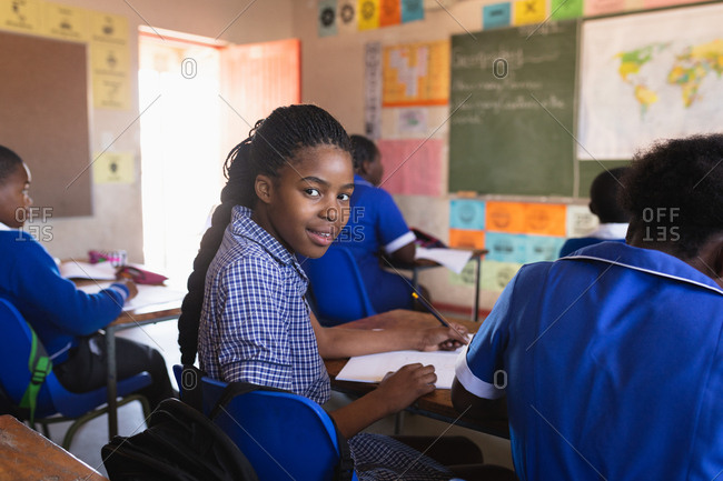 African schoolgirl sitting at her desk and turning around smiling during a lesson in a township elementary school classroom in an elementary school classroom in Cape Town, South Africa