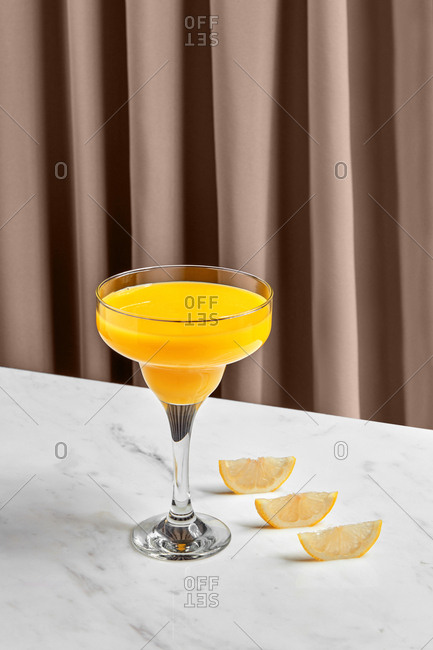 Tasty appetizing orange juice in glass bowl and sliced citrus in row on marble table