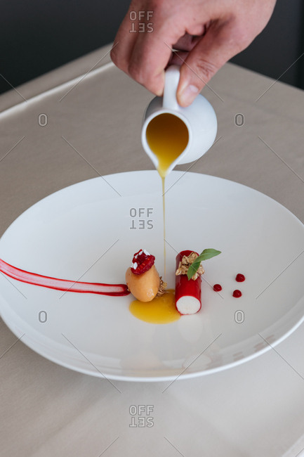 Chef pouring sauce over a gourmet dessert