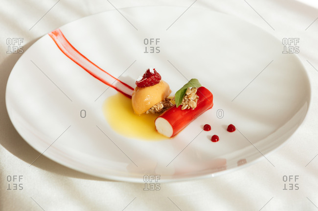 A gourmet dessert with granola, raspberry and sauce