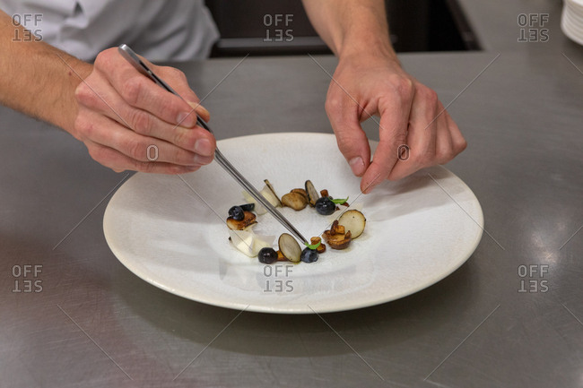 Chef preparing a gourmet dish with tongs in restaurant kitchen