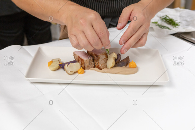 Chef preparing a gourmet meat and mushroom dish in restaurant