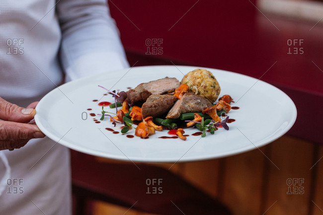Chef carrying a gourmet meat dish with vegetables