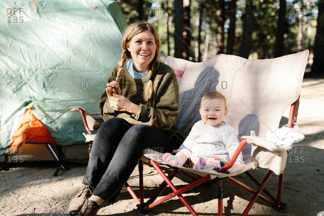 Mother and her baby girl sitting on a camp chair outdoors while camping