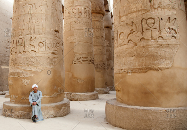 Luxor, Egypt - October 13, 2008: Man sitting by carvings at the Karnak temple complex