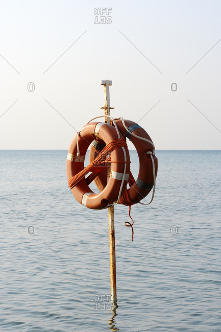 Life belts hanging on pole in sea against clear sky