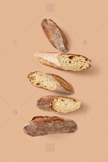From above composition of slices of tasty fresh bread with crunchy crust against beige background