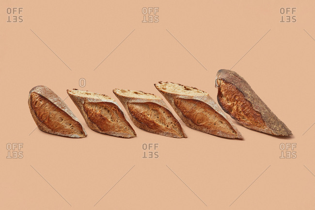 Slices of delicious bread with crunchy crust placed in row against beige background