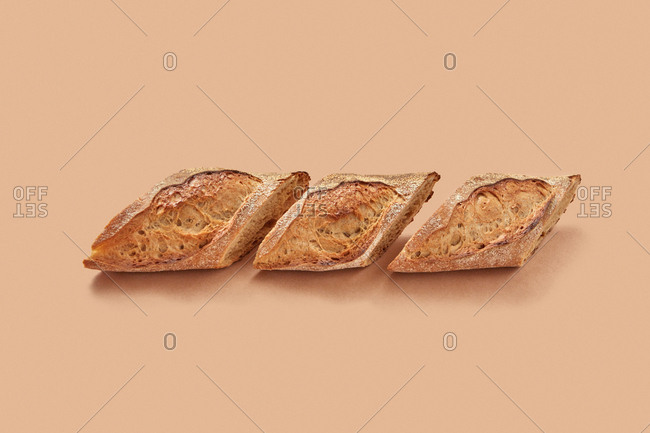 From above pieces of fresh yummy bread arranged in line against beige background