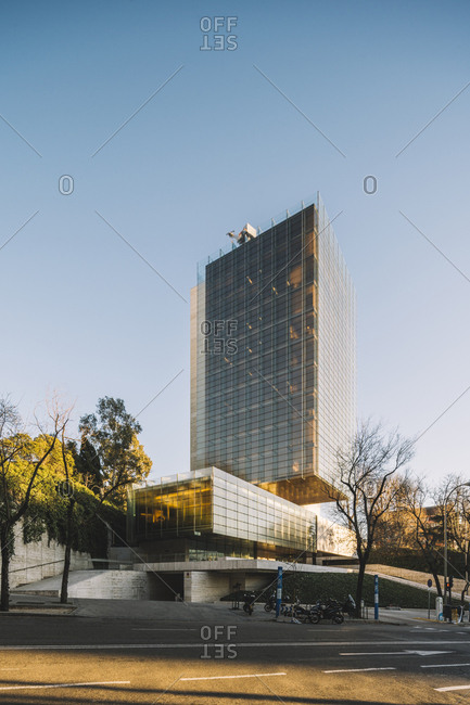 Madrid, Spain - January 2, 2019: Stylish glass skyscraper with parking reflecting sun in bright day in downtown