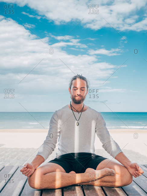 A young man with bare torso sitting in the lotus position Stock