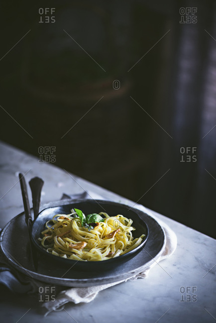 From above appetizing pasta with vegetables basil in black bowl on served table