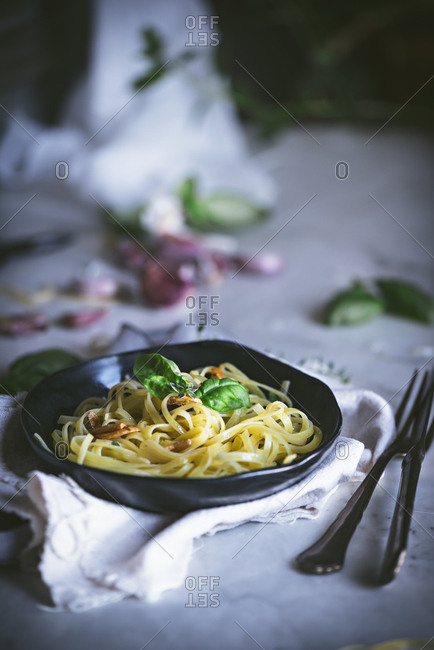 From above appetizing pasta with vegetables basil in black bowl on served table
