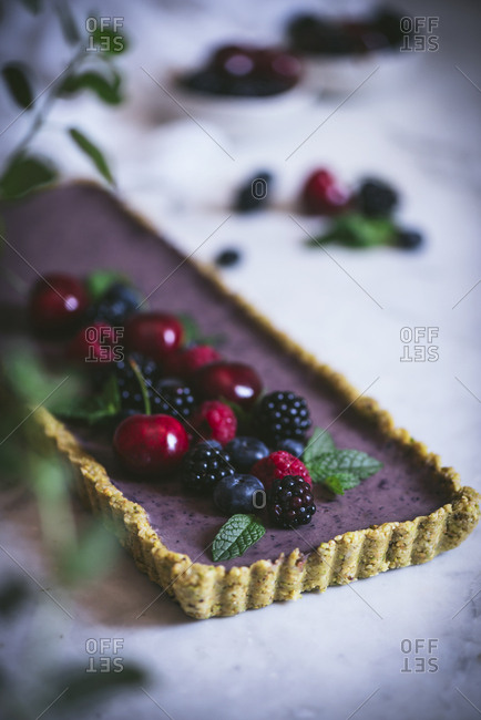 From above ripe tasty cherry blackberry blueberry raspberry with green stems on top of appetizing rectangular cake on white table