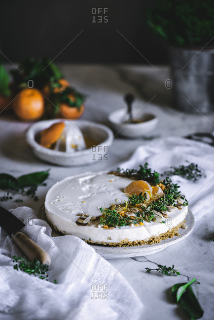 From above tasty appetizing decorated with mandarin green and nuts tangerine cake and whole citruses knife bowl with spoon on table