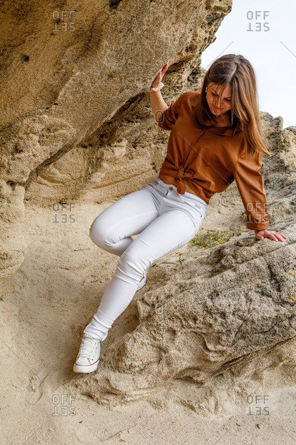 Beautiful adventurous woman in white jeans walking on rocky stones in desert