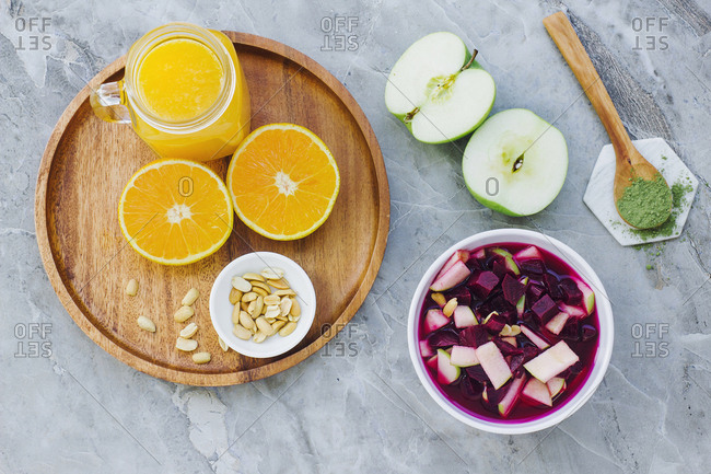 From above served oranges peanuts and orange juice on table with apples condiment and bowl of beets and apples