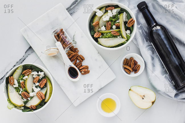 Served bowls with cut pears and pecan on table with pear walnuts and bottle of soy sauce