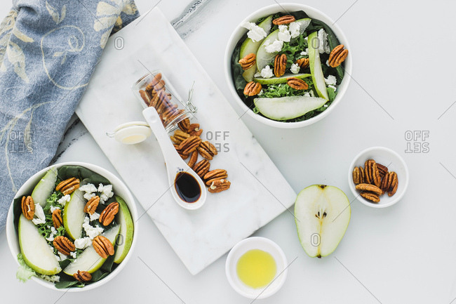 Served bowls with cut pears and pecan on table with pear walnuts and a spoon of soy sauce