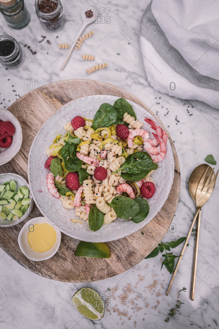 From above appetizing salad and sauce berry sliced lime on wooden stand with salt and pepper on table