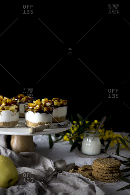 Assorted delicious desserts and snacks placed on table near napkin and flowers against black background