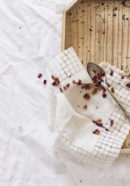 From above dried tea leaves and aromatic petals placed on napkin and tray over white fabric