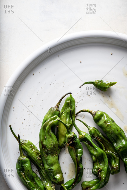 Close up of shishito peppers on plate on white background