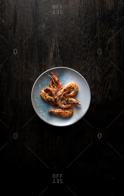 Overhead view of a plate of shrimp on dark wooden background