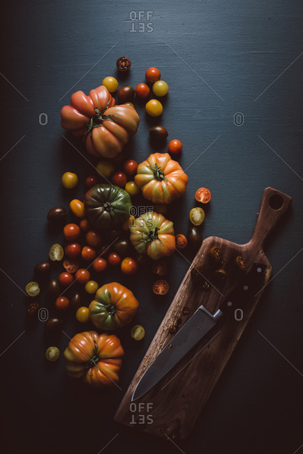 Variety of heirloom tomatoes on dark background with cutting board and knife