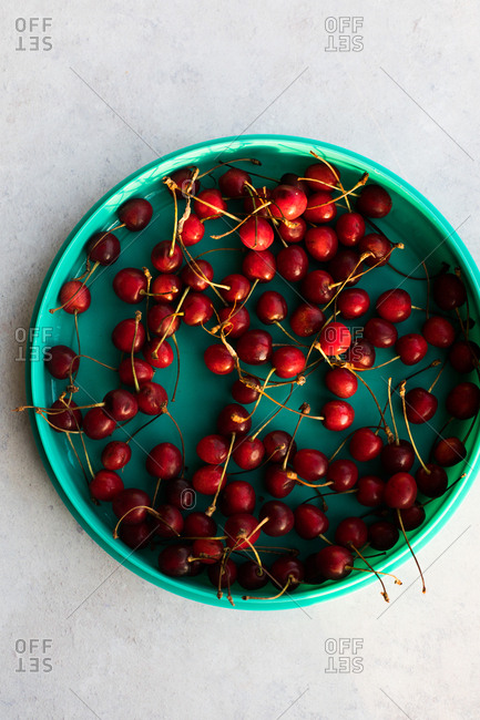 Cherries in a teal dish on light background