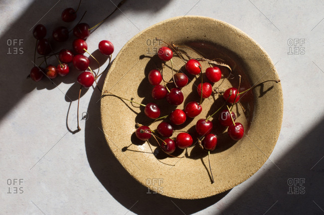 Cherries in a handmade bowl on light background
