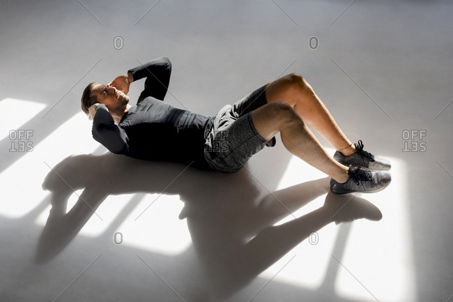 Athlete doing crunches in sunlit studio